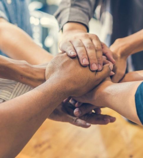 A group of people holding hands in the middle of a circle.